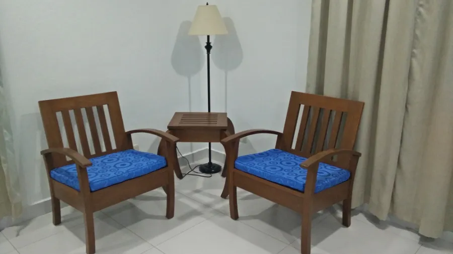 Two wooden armchairs with blue cushions, a side table and a floor lamp